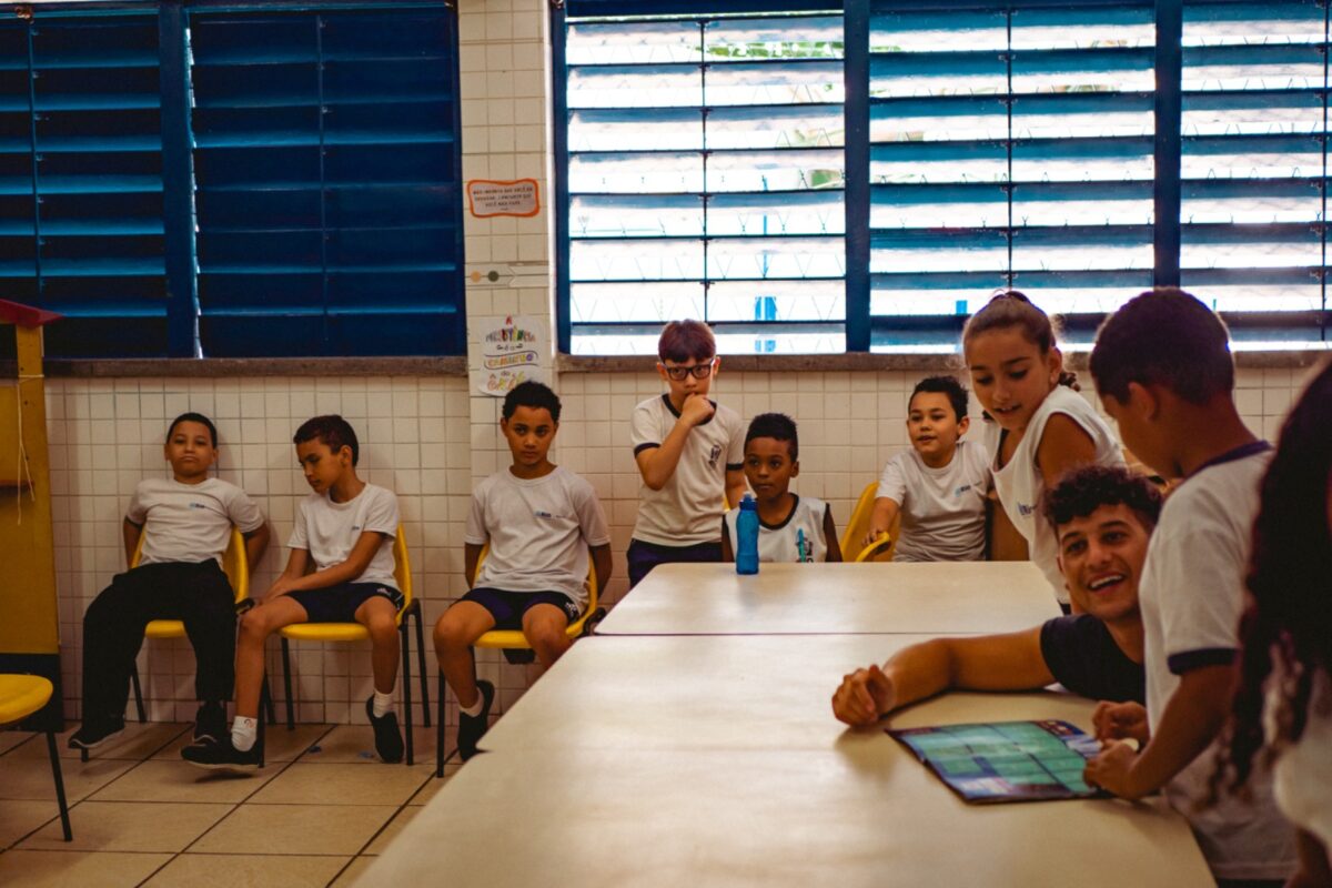 Estudante do ensino fundamental mostra álbum oficial da Copa do Mundo 2022 para estudante de intercâmbio argentino. (Foto de Helena Erin)